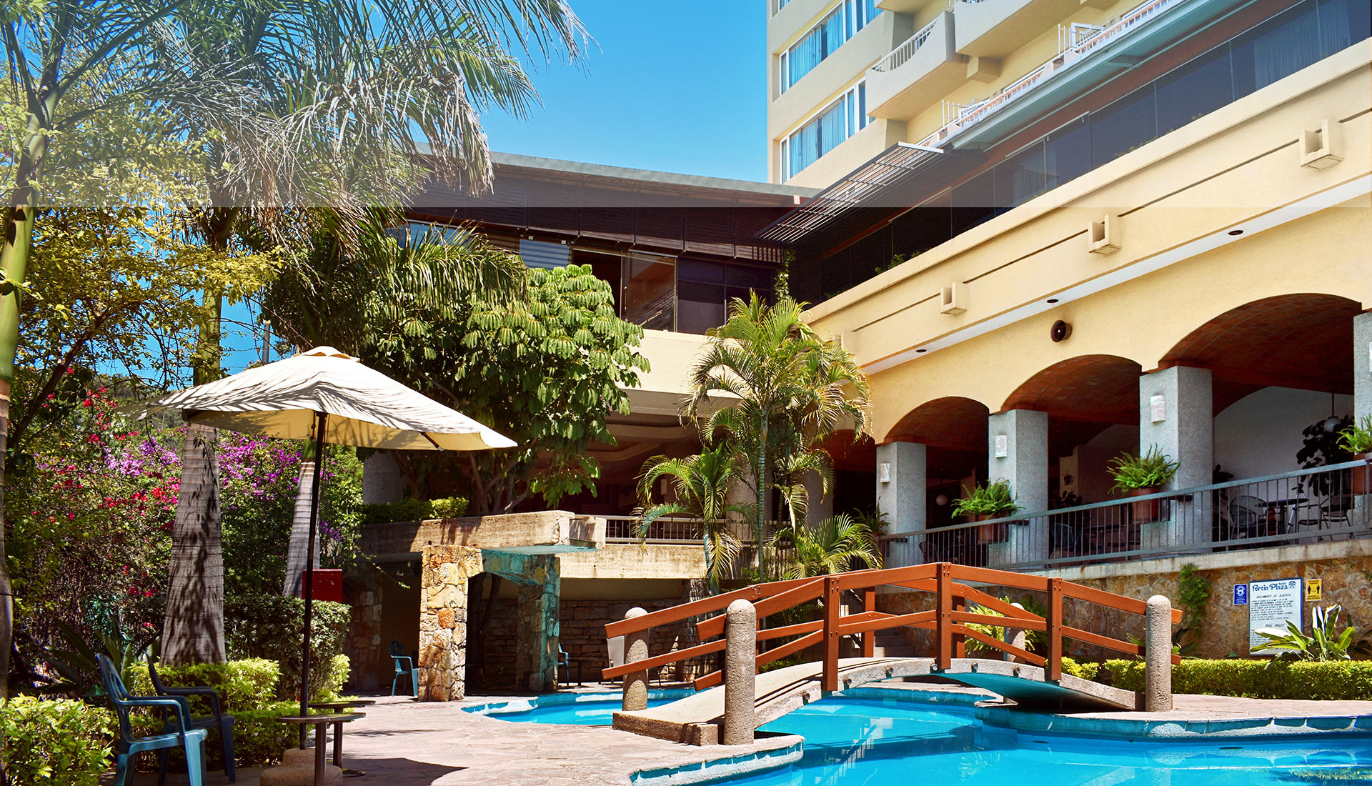 Tropical pool area at Fortín Plaza Hotel in Oaxaca with bridge, lounge seating, and lush landscaping—ideal for MICE incentive travel and post-event relaxation.